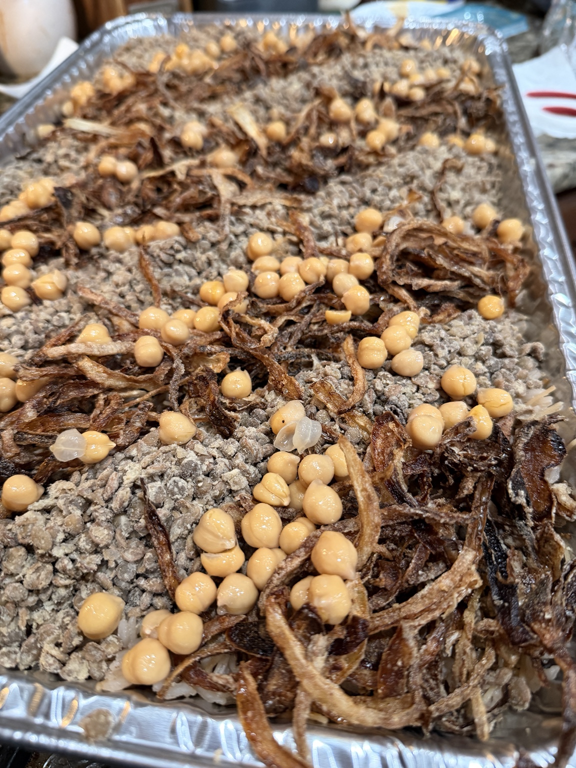 Catering tray of koshary topped with chickpeas and fried onions
